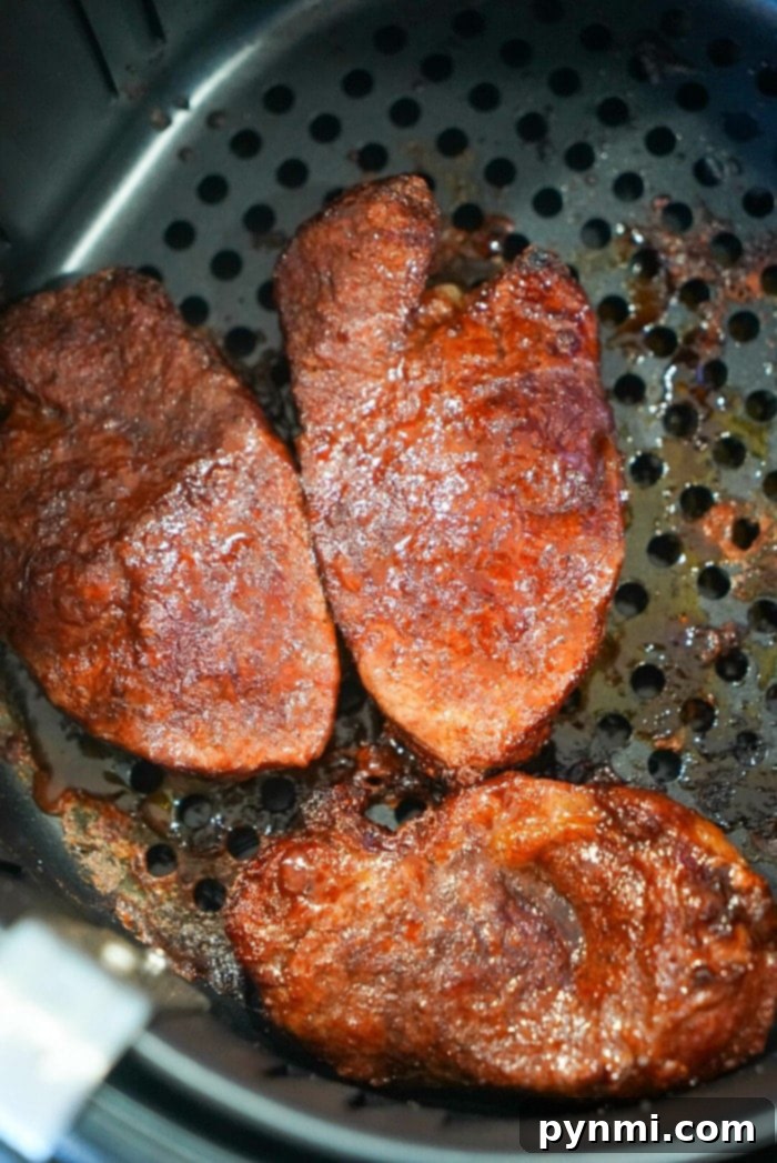 Three seasoned filets cozy up next to a perfectly cooked air fryer filet mignon in the basket.
