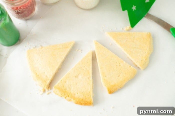Freshly baked Christmas Tree Sugar Cookies on a cooling rack, glistening with green icing and festive sprinkles.