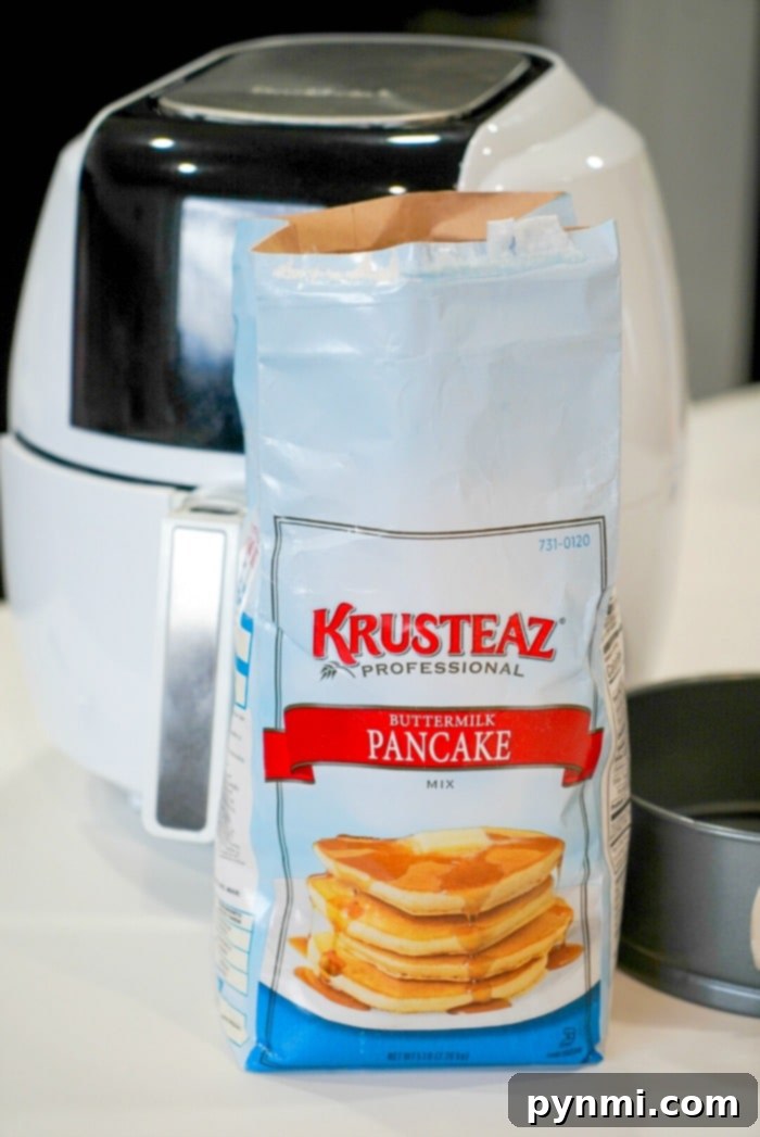 A freshly cooked, golden-brown pancake being carefully removed from a springform pan in an air fryer with a spatula.