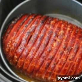 A perfectly glazed air fryer ham with scored lines, expertly cooked and nestled inside the pot.