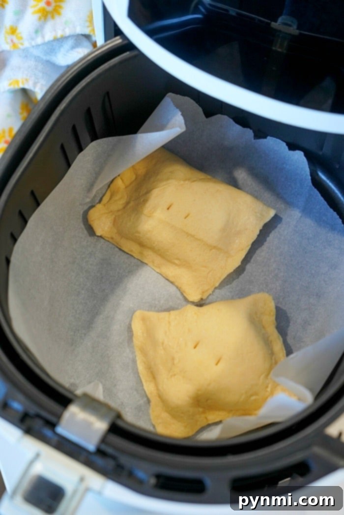 Air fryer hand pies in the basket, perfectly golden brown and ready to be drizzled with icing.