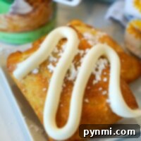 Pastry topped with icing and powdered sugar, with a can of apple filling, and raw air fryer dumplings in the background.