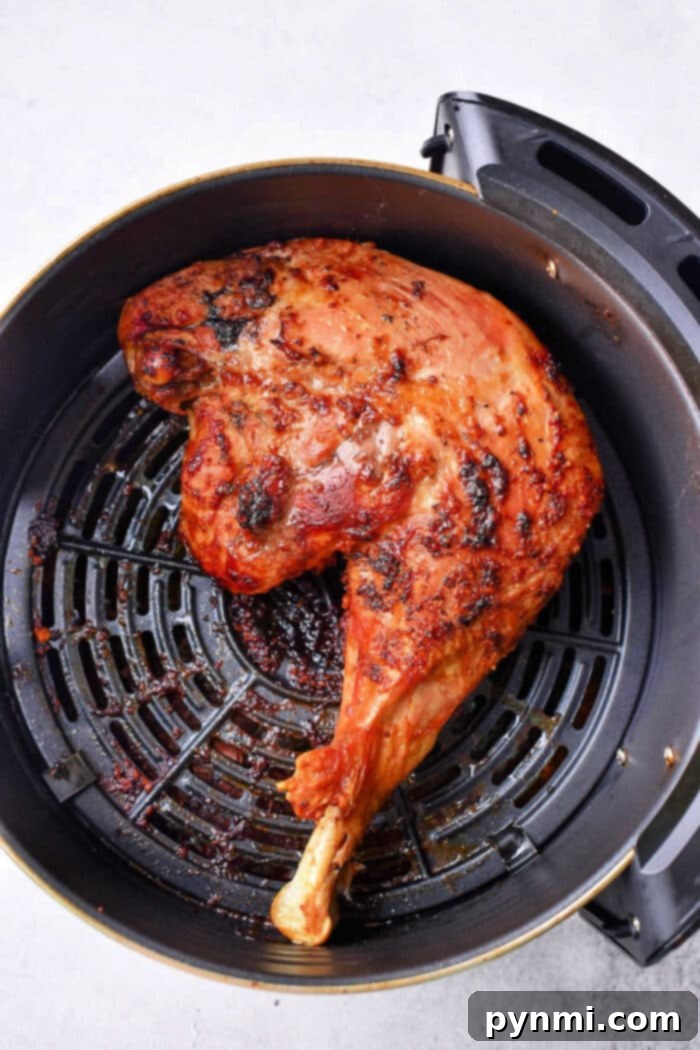 Juicy and Crispy Air Fryer Chicken Quarters 2 Cooked chicken leg quarters in an air fryer basket, with crispy browned skin, reminiscent of perfectly cooked air fryer chicken leg quarters.