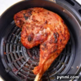 Cooked chicken leg quarters in an air fryer basket, with crispy browned skin, reminiscent of perfectly cooked air fryer chicken leg quarters.