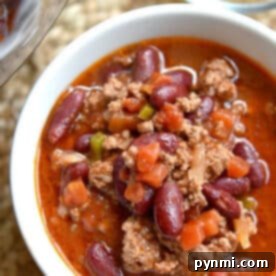A bowl of instant pot chili with ground meat, red kidney beans, and diced vegetables in a rich, red sauce.