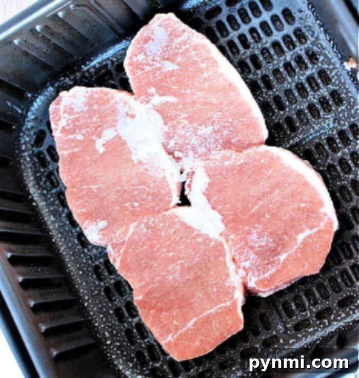 Two perfectly cooked frozen pork chops, expertly sliced to reveal a juicy, tender interior, beautifully garnished on a white plate, ready for serving.