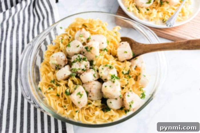 Golden Air Fryer Scallops 7 Bowl of pasta topped with air fryer scallops and chopped herbs, served with a wooden spoon.