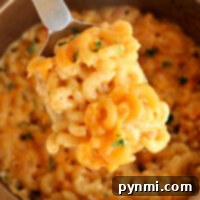 A spoonful of creamy air fryer mac and cheese in a casserole dish.