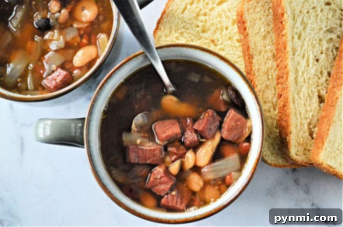 Ultimate Instant Pot 15-Bean Comfort 6 Instant pot Bean Soup in a serving bowl with a spoon.