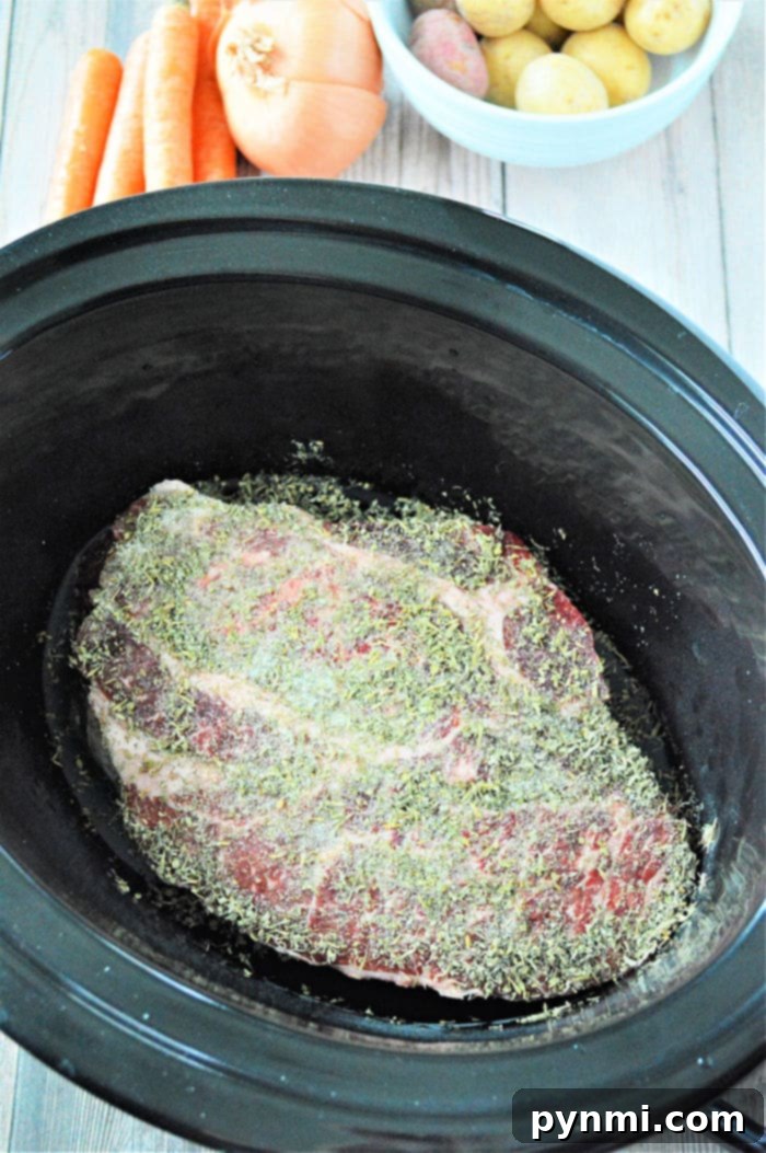No Thaw Slow Cooker Pot Roast 9 A large, juicy frozen roast, slow-cooked to perfection in a Crockpot, resting on a cutting board, ready to be shredded.