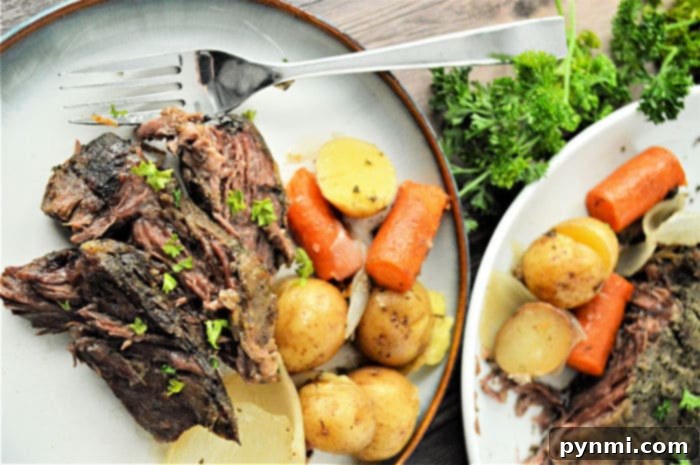 No Thaw Slow Cooker Pot Roast 10 A serving of tender shredded roast beef with carrots, potatoes, and a rich gravy, showcasing a delicious homemade meal.