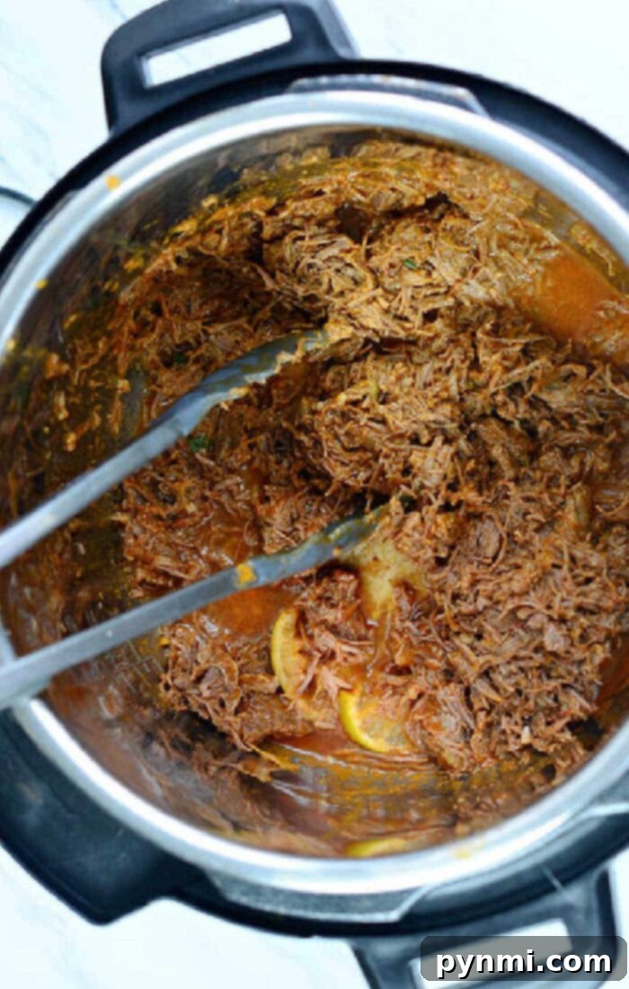 Mouthwatering Instant Pot Barbacoa 10 Ninja Foodi Barbacoa – A close-up of a serving of Ninja Foodi barbacoa beef with fresh toppings, showcasing its tender texture.