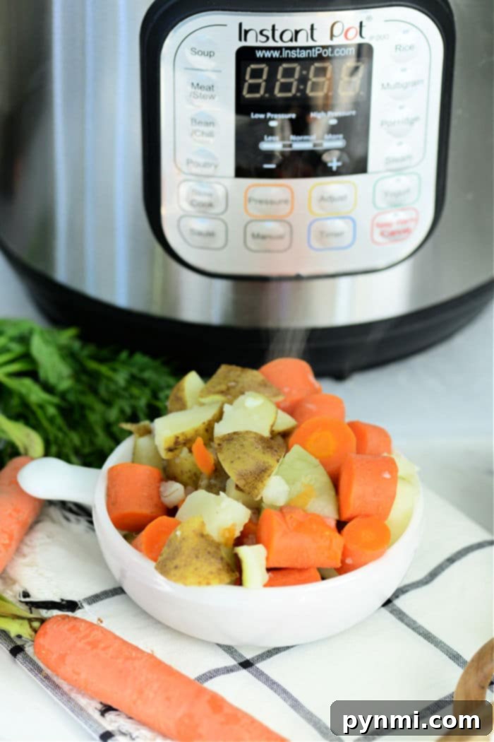 Easy Instant Pot Potatoes and Carrots 5 An open Instant Pot showing perfectly cooked potatoes and carrots in a steamer basket