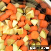 Chopped carrots and potatoes simmer gently in an Instant Pot, transforming the water into a fragrant, savory broth.