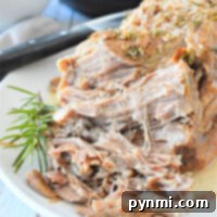 Shredded pork with herbs on a white plate, garnished with a sprig of rosemary.