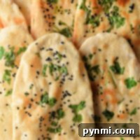 Close-up of naan bread, part of a homemade naan recipe, sprinkled with black seeds and fresh cilantro.