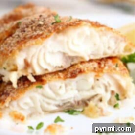 Two pieces of baked, breaded white fish fillets—similar to air fryer catfish—garnished with chopped parsley on a white plate.