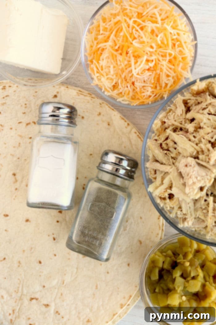 Ingredients laid out for air fryer chimichangas: large flour tortillas, shredded cheese, shredded chicken, diced green chiles, cream cheese, salt, pepper, and olive oil spray.