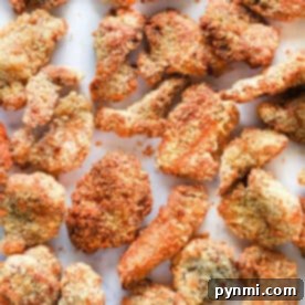 Crispy, golden-brown air fryer popcorn chicken pieces arranged on a white surface.
