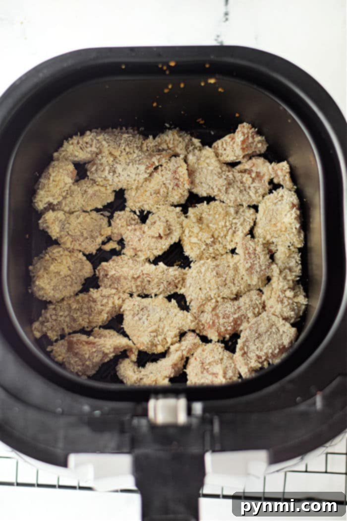 Crispy Air Fryer Popcorn Chicken 7 Crispy popcorn chicken pieces arranged in an air fryer basket, ready to be served.