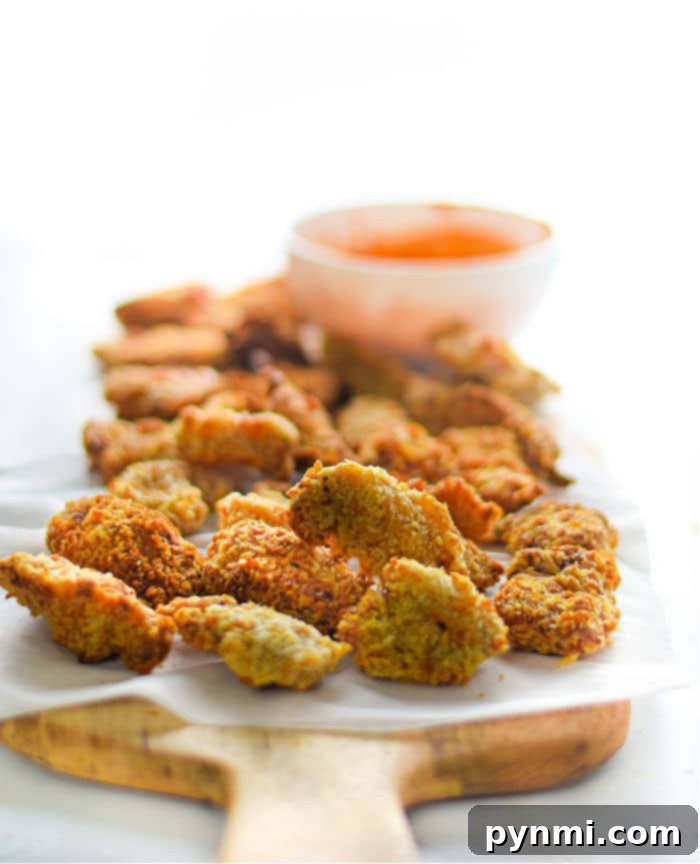 Crispy Air Fryer Popcorn Chicken 8 A serving of homemade popcorn chicken, garnished with fresh parsley and ready to be enjoyed with dipping sauces.