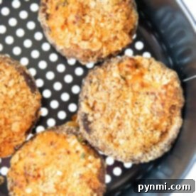 Four air fryer stuffed mushrooms with a golden breadcrumb topping served fresh from the basket.