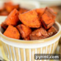 Golden-brown roasted sweet potato cubes, perfectly seasoned and nestled in a ceramic dish, achieve their crisp perfection with the help of an air fryer.