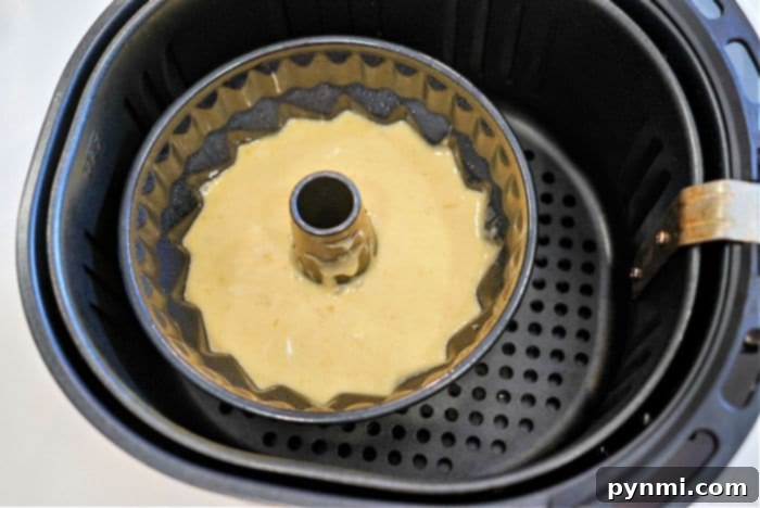 A freshly baked, golden brown banana bread bundt cake in an air fryer basket, ready to be removed.