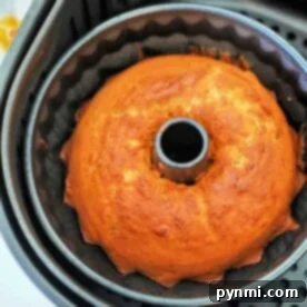 Golden brown banana bread cake in a bundt pan inside an air fryer basket.