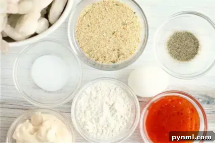 Ingredients arranged on a white surface: a small bowl of bread crumbs, black pepper, a white egg, flour, a red sauce for the bang bang shrimp, mayonnaise, salt, and a bowl of raw shrimp ready for the air fryer.