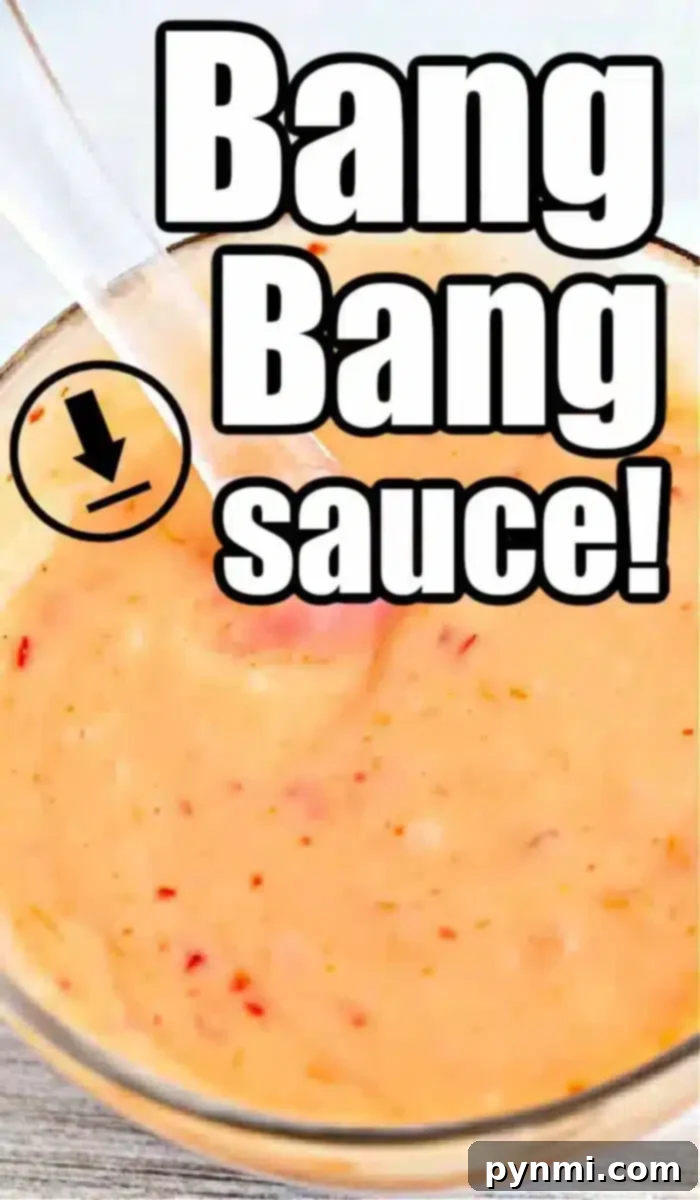Creamy Zesty Shrimp Sauce 2 A close-up of a bowl filled with creamy, orange-colored bang bang shrimp sauce, sprinkled with visible red specks. A clear spoon dips into the savory mix. Bold text overlay reads, 'Bang Bang Sauce!'