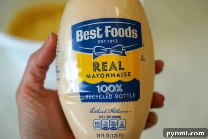 Creamy Zesty Shrimp Sauce 3 A person holds a 20 fl oz bottle of Best Foods Real Mayonnaise, labeled '100% Recycled Bottle.' Perfect for crafting the ultimate bang bang shrimp sauce, this mayo offers 100 calories per tablespoon serving and nutrition facts right on the label.