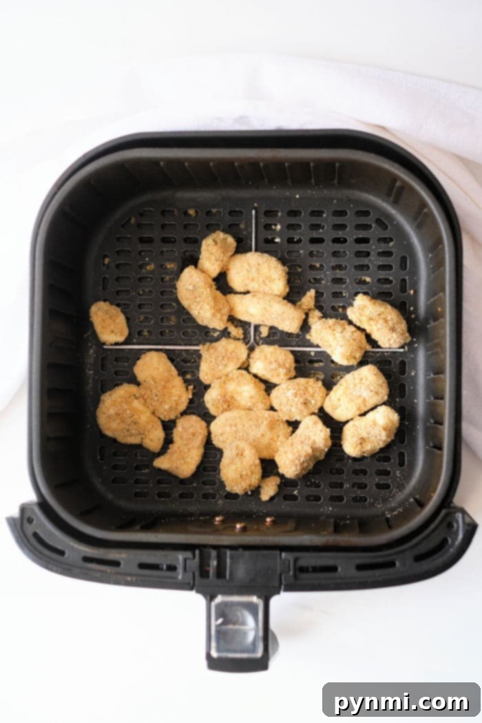 Golden Crispy Air Fryer Cheese Curds 9 Crispy cheese curds cooling in an air fryer basket after cooking.