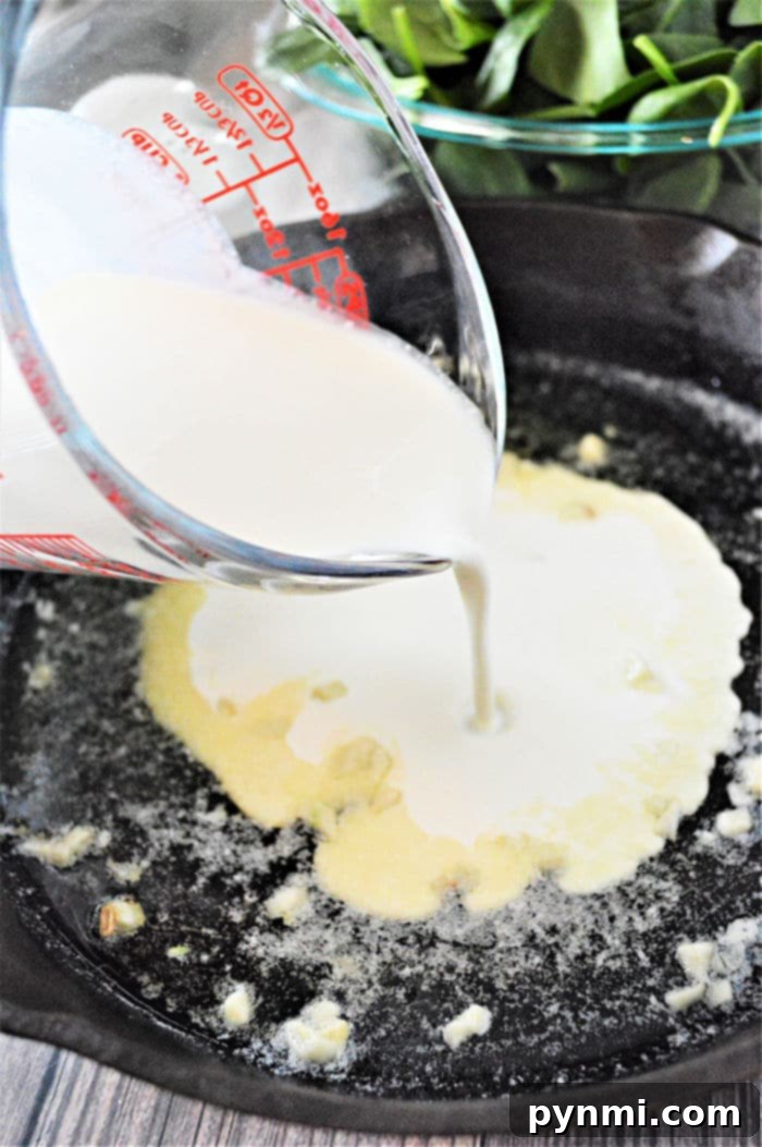 Homemade creamed spinach cooking in a large cast iron skillet, bubbling gently, showing its rich and creamy texture.