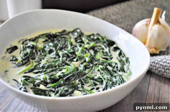 Creamed spinach served in a small white bowl next to a perfectly cooked steak, highlighting its role as an ideal side dish for various entrees.