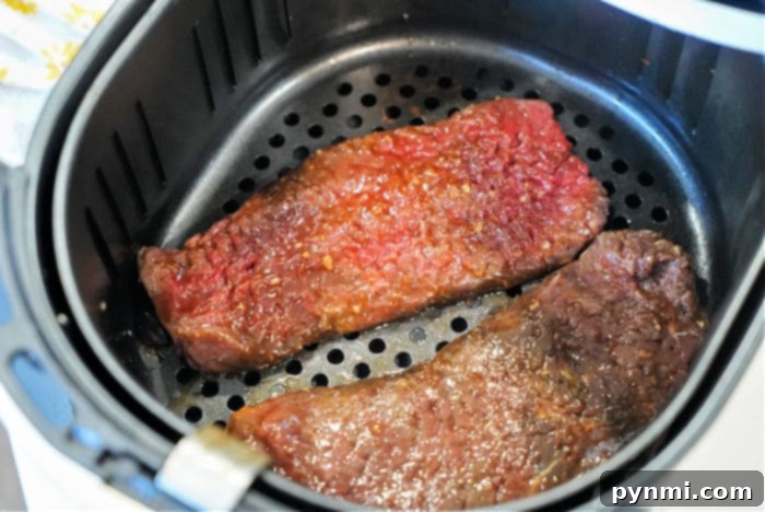 Crispy Golden Air Fryer Cube Steaks 8 Two pieces of raw, marinated cube steak perfectly arranged in an air fryer basket, ready for cooking.