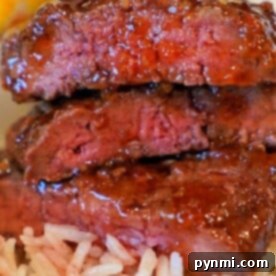 Three pieces of cube steak, cooked to perfection in an air fryer, stacked on a bed of fluffy white rice.