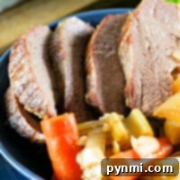 Sliced tri tip beef with tender carrots and vegetables sits invitingly in a blue bowl on a wooden board, reminiscent of a hearty Dutch oven meal.