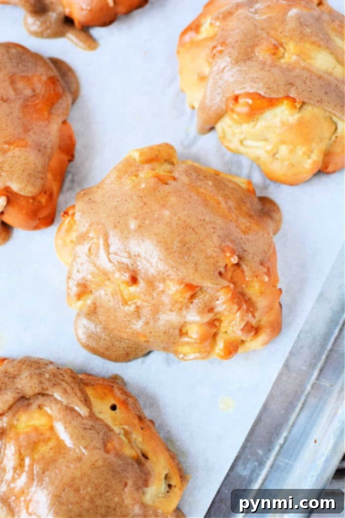 Golden brown air fryer apple fritters piled high, drizzled with a sweet glaze, on a white plate.