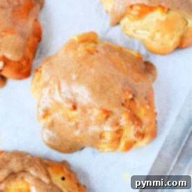 Air fryer apple fritters with a delectable cinnamon glaze rest perfectly on parchment paper.