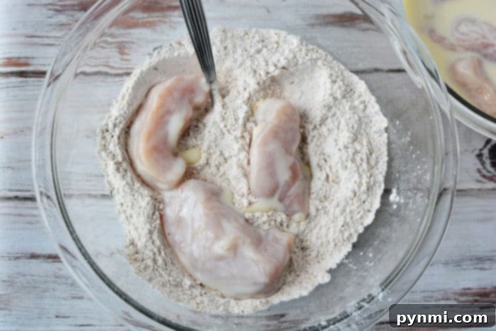 Chicken pieces soaking in a bowl of buttermilk, ready for breading.