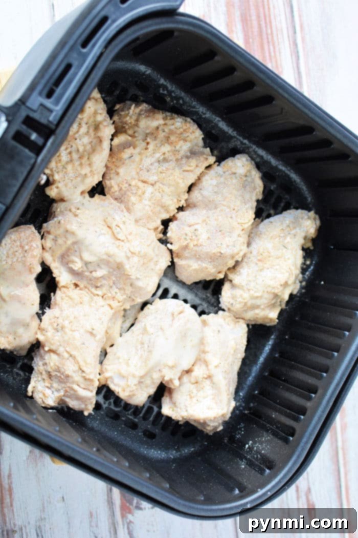 Close-up of golden, perfectly fried chicken pieces in an air fryer basket, showing their crispy texture.