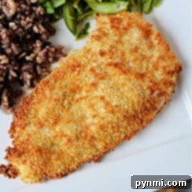 A breaded chicken cutlet sits elegantly on a plate alongside vibrant green beans and a medley of mixed rice, creating an inviting meal reminiscent of crispy chicken cutlets made effortlessly in an air fryer.