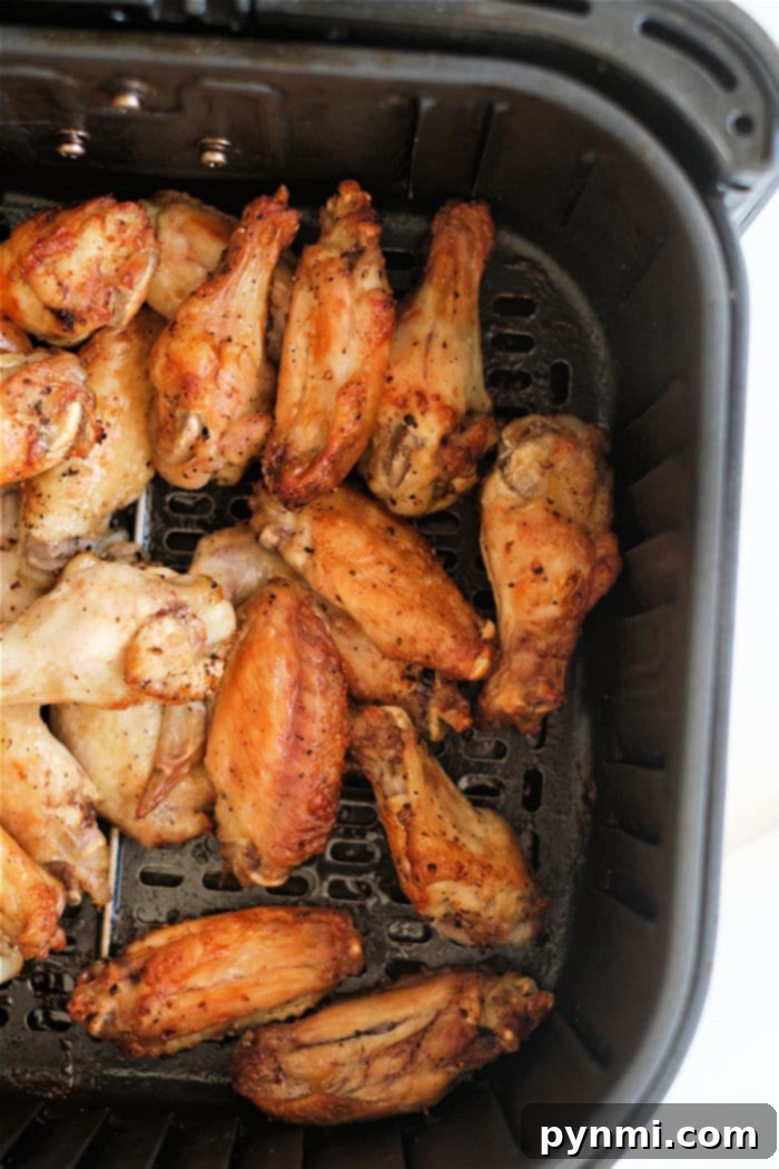 Close-up of air fryer lemon pepper chicken wings on a serving dish, garnished with fresh lemon wedges.