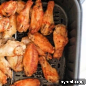 Cooked lemon pepper chicken wings in an air fryer basket.