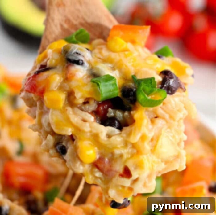 Instant Pot Mexican Fiesta Chicken and Rice 11 A wooden spoon holds cheesy rice with black beans, corn, and diced tomatoes, garnished with green onions—an instant pot Mexican chicken and rice delight.