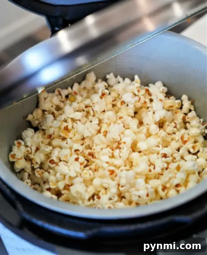 A pot filled with freshly popped popcorn inside an open Ninja Foodi pressure cooker.