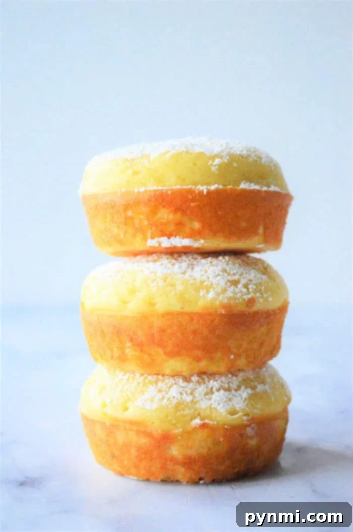 Fluffy Bisquick Muffins in Minutes 2 Three stacked lemon fluffy Bisquick muffins, are delicately dusted with powdered sugar on a light background.