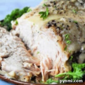 Frozen pork roast cooked in an Instant Pot with herbs, sliced and served on a plate garnished with fresh parsley.