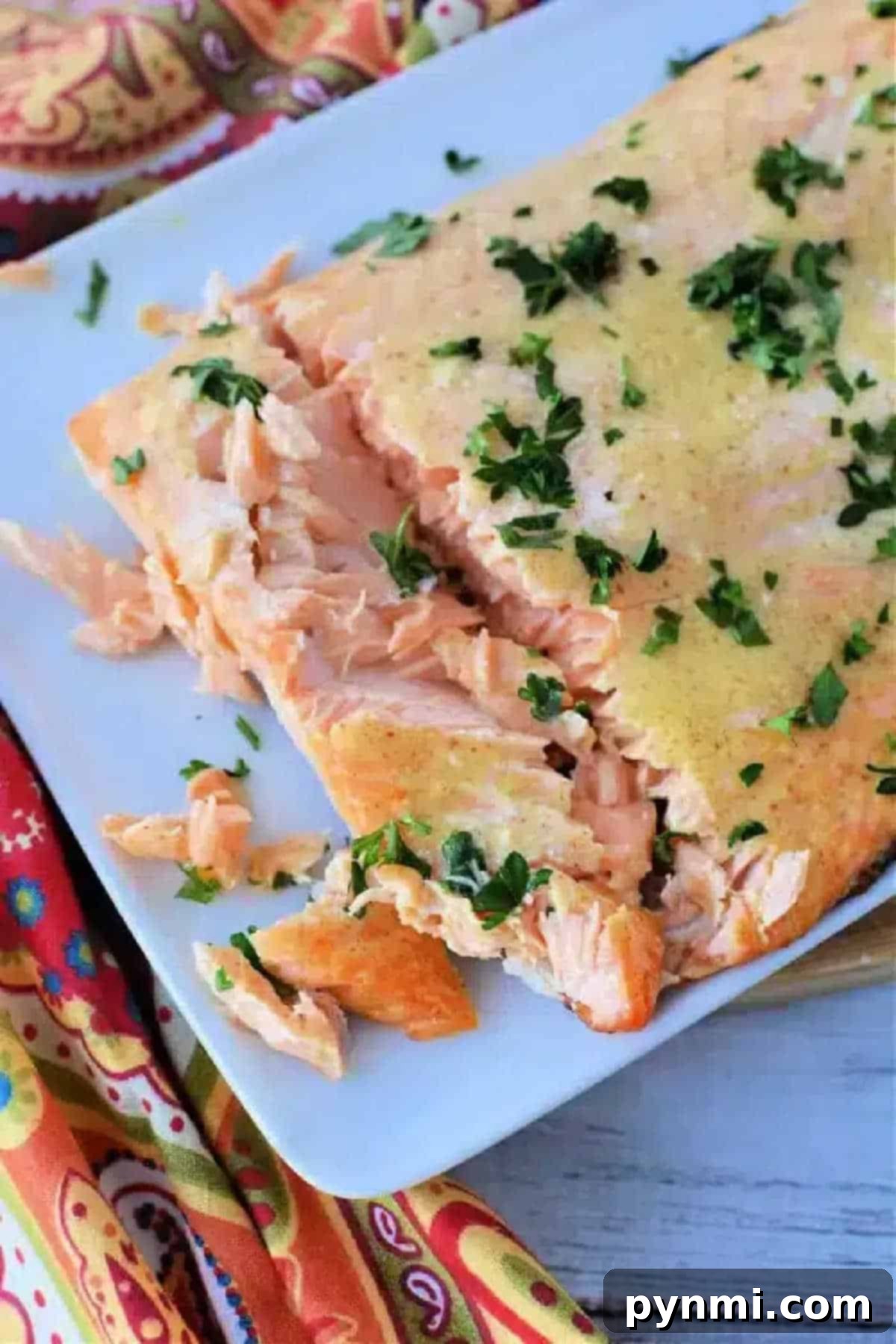 Perfectly cooked frozen salmon in air fryer, garnished with fresh chopped herbs on a white plate, showing its flaky texture.